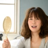 鏡を持って髪に悩んでいる女性