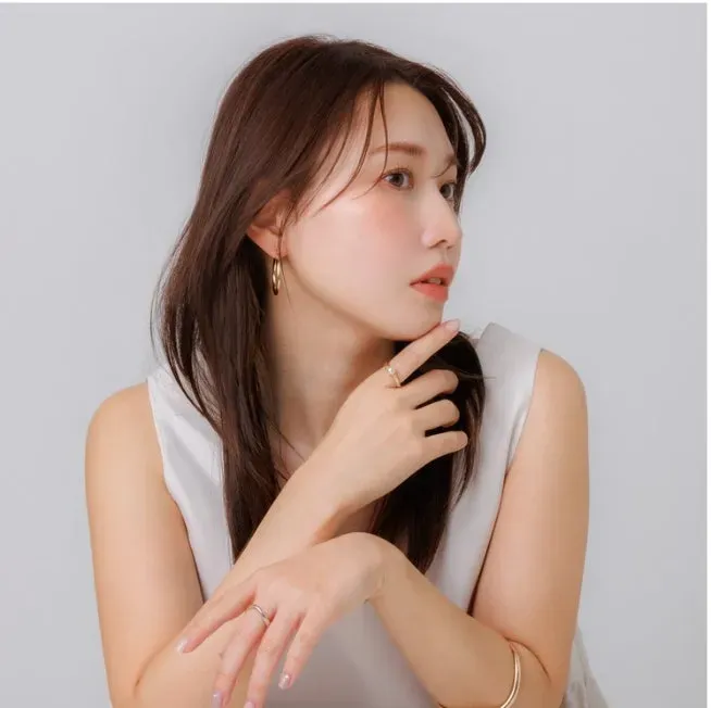 女性が指に指輪をはめ、イヤリングとブレスレットを身につけているポートレート写真です。